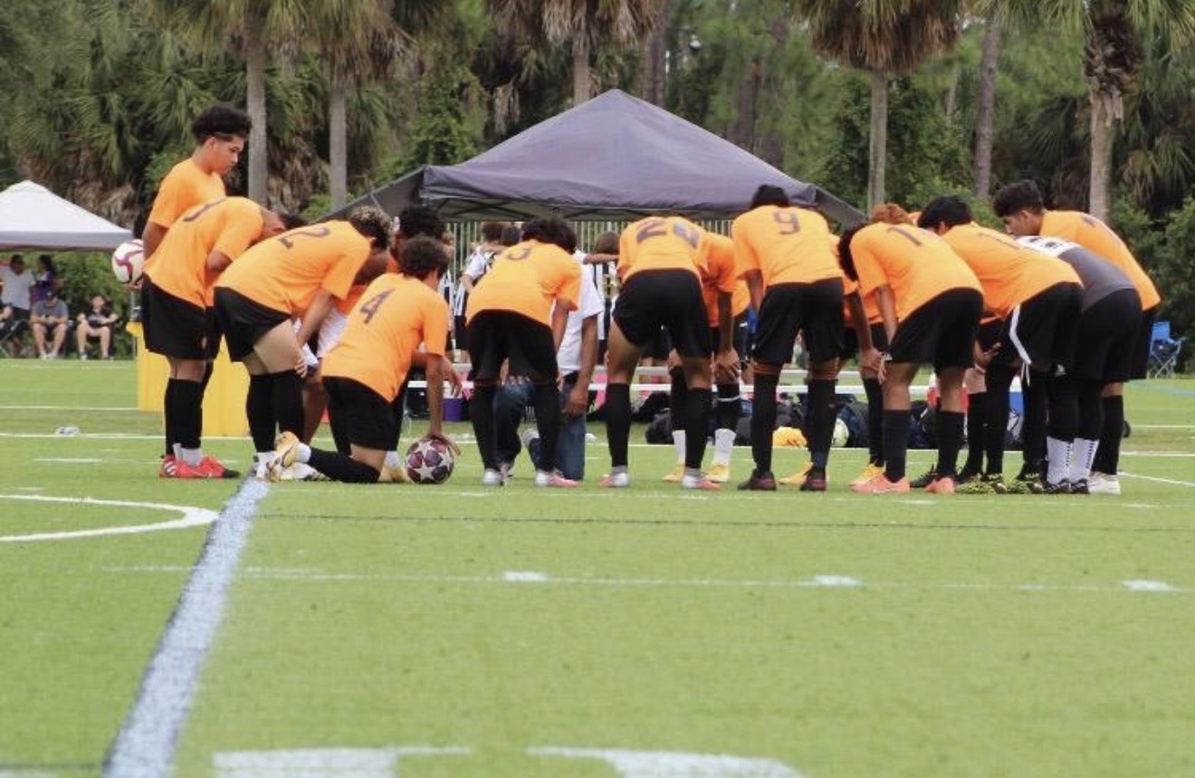 Players bowed in pre-match huddle on the pitch