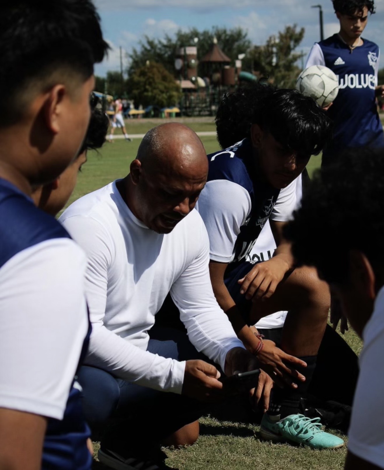 Coach with players reviewing tactics on the sideline